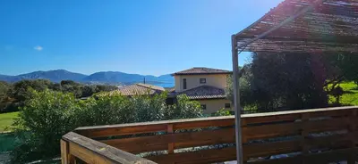 a wooden fence with a view of a house at Duo de Mini-villas, gîtes chaleureux & vue mer in Olmeto