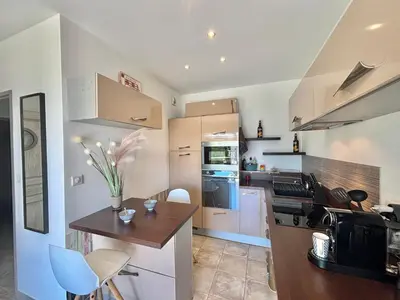 a kitchen with white cabinets and a table and chairs at Appartement Altu Mare 2 pièces avec terrasse AGOSTA PORTICCIO in Albitreccia