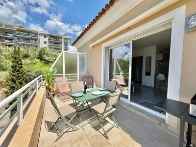 a patio with a table and chairs on a balcony at Appartement Altu Mare 2 pièces avec terrasse AGOSTA PORTICCIO in Albitreccia