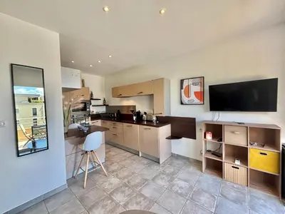a kitchen with a table and a tv on the wall at Appartement Altu Mare 2 pièces avec terrasse AGOSTA PORTICCIO in Albitreccia