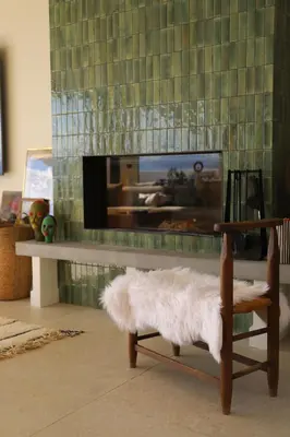 a living room with a fireplace with a tv and a chair at Villa Rétine in Ajaccio