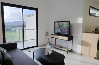 a living room with a tv and a large window at A Macchia - T2 nature & couché de soleil in Figari