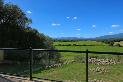 a view of a field from a balcony at A Macchia - T2 nature & couché de soleil in Figari