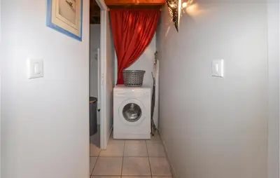 a hallway with a washing machine and a red curtain at Cozy Apartment In Cuttoli With Wifi in Cuttoli-Corticchiato