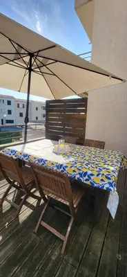 a table and chairs with an umbrella on a deck at Bright apartment in Albitreccia near beach in Albitreccia