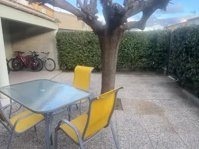 a table and two yellow chairs next to a tree at Pavillon au bord de la mer in Poggio-Mezzana