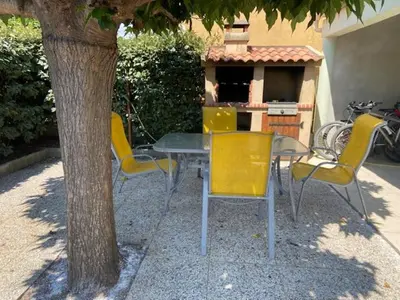 a table and chairs sitting next to a tree at Pavillon au bord de la mer in Poggio-Mezzana