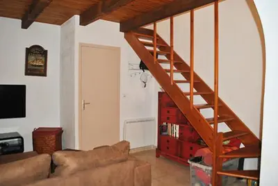 a living room with a couch and a wooden staircase at Pavillon au bord de la mer in Poggio-Mezzana