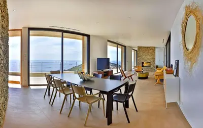 a dining room with a table and chairs and a living room at Villa petra mare in Cargèse