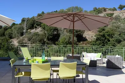 a patio table with yellow chairs and an umbrella at A Casa Ghjalla in Cauro