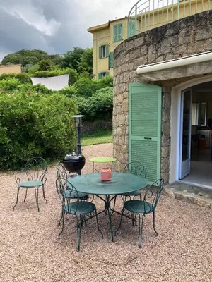 a patio table and chairs with a green door at A Casa Ghjalla in Cauro