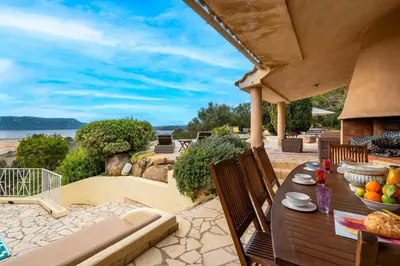 a patio with a table and chairs with a view of the ocean at Villa de standing piscine- vue mer panoramique in Porto-Vecchio