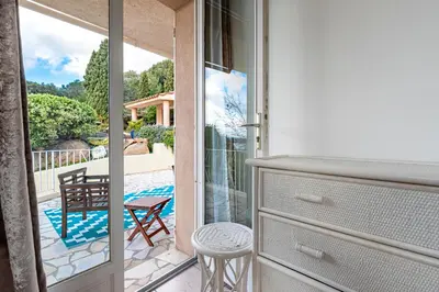 a sliding glass door to a patio with a table and a chair at Villa de standing piscine- vue mer panoramique in Porto-Vecchio