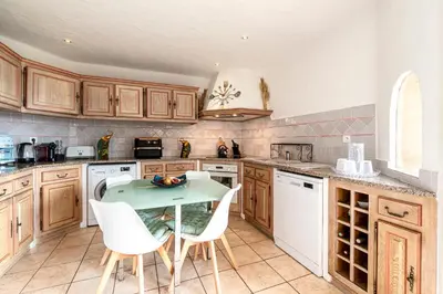 a kitchen with wooden cabinets and a table and chairs at Villa de standing piscine- vue mer panoramique in Porto-Vecchio