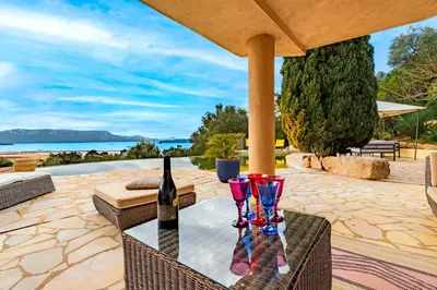 a table with a bottle of wine and two glasses at Villa de standing piscine- vue mer panoramique in Porto-Vecchio