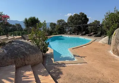 a swimming pool in a yard with a large rock at Villa Tonnara - Maison du soleil in Sotta
