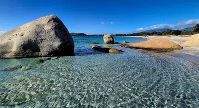 a beach with rocks and clear water on a beach at Résidence Luna, Saint-Cyprien in Porto-Vecchio