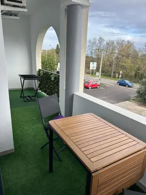 a balcony with a wooden table and a chair at Appartement T2 calme et paisible Vescovato in Venzolasca