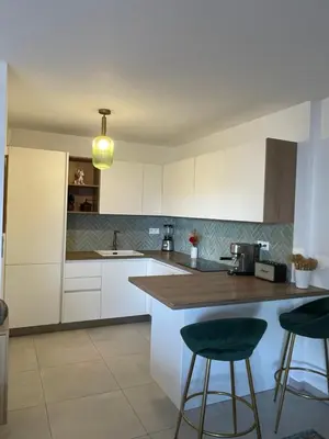 a kitchen with white cabinets and a counter with stools at charmant appartement a ajaccio in Ajaccio