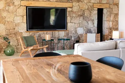 a living room with a tv on a stone wall at Villa Neuve Corse sud avec vue mer et piscine chauffée in Pianottoli-Caldarello