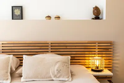 a bed with a wooden headboard with a lamp at Villa Neuve Corse sud avec vue mer et piscine chauffée in Pianottoli-Caldarello