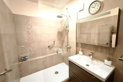 a bathroom with a sink and a shower with a clock on the wall at Bright apartment with balcony in Ajaccio in Ajaccio