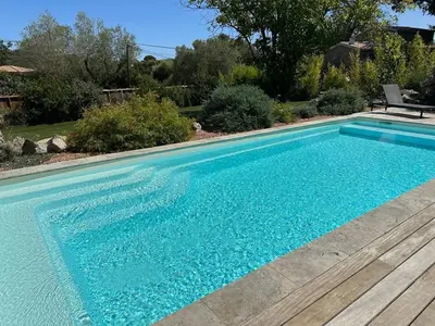 a swimming pool with blue water in a yard at Villa Aria Natura, calme sérénité piscine chauffée in Porto-Vecchio