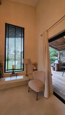 a living room with a chair and a window at Villa Aria Natura, calme sérénité piscine chauffée in Porto-Vecchio