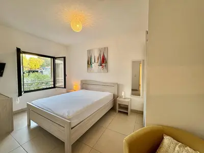 a bedroom with a bed and a window and a chair at T2 au cœur de Propriano in Propriano