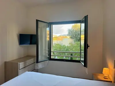 a bedroom with a bed and a large window at T2 au cœur de Propriano in Propriano
