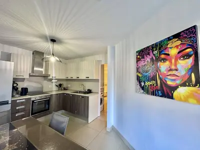 a kitchen with a large painting of a woman on the wall at T2 au cœur de Propriano in Propriano