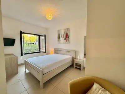 a bedroom with a bed and a chair and a window at T2 au cœur de Propriano in Propriano