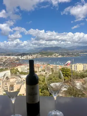a bottle of wine and two wine glasses on a ledge at T2 avec vue panoramique in Ajaccio