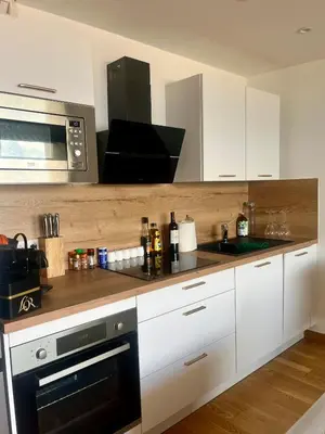 a kitchen with white cabinets and a microwave at T2 avec vue panoramique in Ajaccio