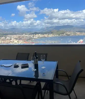 a table with two wine glasses and a large window at T2 avec vue panoramique in Ajaccio