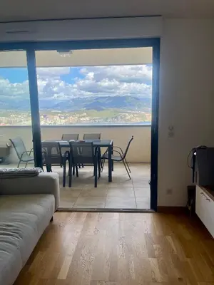 a room with a table and chairs and a large window at T2 avec vue panoramique in Ajaccio