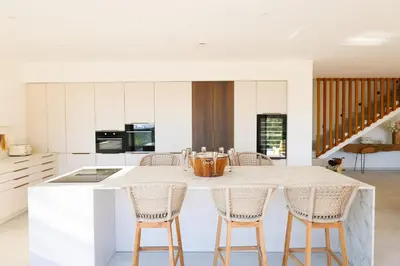 a kitchen with a large white island with chairs at Villa Aberia Di Santa Lucia in Sainte-Lucie de Porto-Vecchio