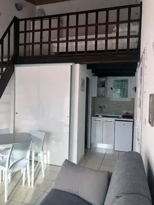 a living room with a couch and a table and a kitchen at Bungalow 4 people - Marea Resort in Santa-Lucia-di-Moriani