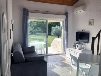 a living room with a couch and a sliding glass door at Bungalow 4 people - Marea Resort in Santa-Lucia-di-Moriani