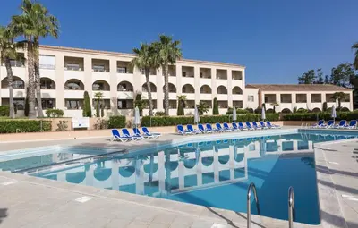 a swimming pool with blue chairs and a building at T2 - next to the sea in Linguizzetta