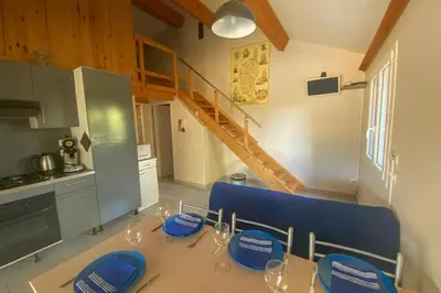 a dining room with a table and blue chairs at Cozy mini villa proche plages, calme & activés in Bonifacio