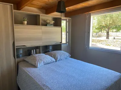 a bedroom with a bed with a large window at Cozy mini villa proche plages, calme & activés in Bonifacio