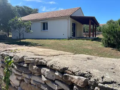 a house with a stone wall in front of it at Cozy mini villa proche plages, calme & activés in Bonifacio