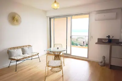 a living room with a table and a chair and a window at Bright studio with sea view in Ajaccio in Ajaccio