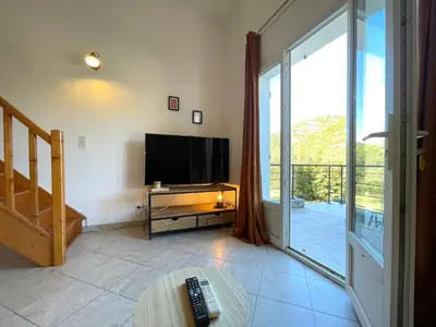 a living room with a television and a sliding glass door at Charmant Duplex à la campagne in Riventosa