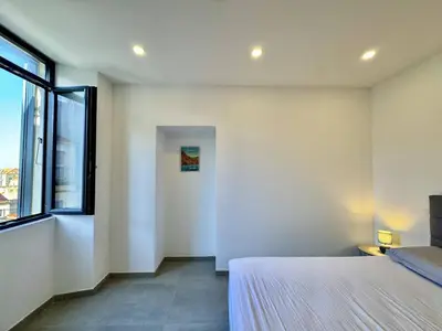 a bedroom with a bed and a large window at Magnifique T3 tout confort in Propriano