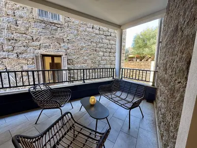 a balcony with chairs and a table and a stone wall at Magnifique T3 tout confort in Propriano