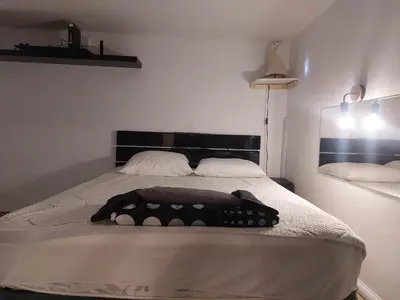 a white bedroom with a bed with a black headboard at AJACCIO GRAND STUDIO LOFT VUE MER ET MONTAGNE 5 p in Ajaccio