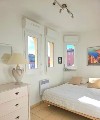 a bedroom with a bed and a dresser with windows at Appartement Cosy Port de Porto-Vecchio in Porto-Vecchio