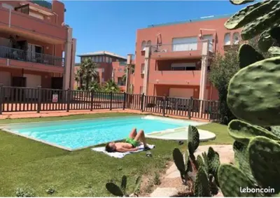 a man laying in the grass next to a swimming pool at Appartement Cosy Port de Porto-Vecchio in Porto-Vecchio